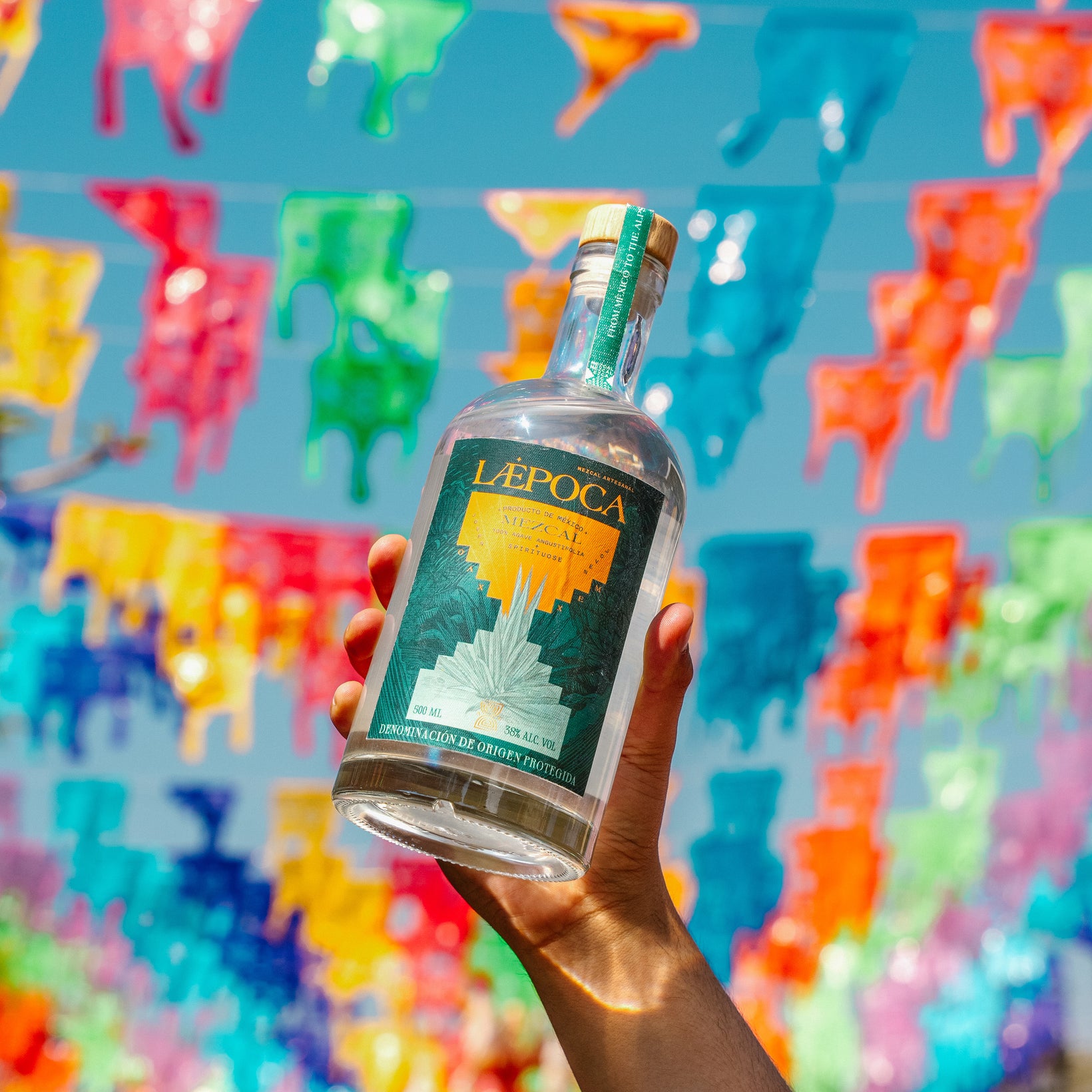 Zwei Hände stoßen mit Mezcal an, eine Hand aus Oaxaca, eine aus den Alpen. LÆPOCA-Markenmotiv.